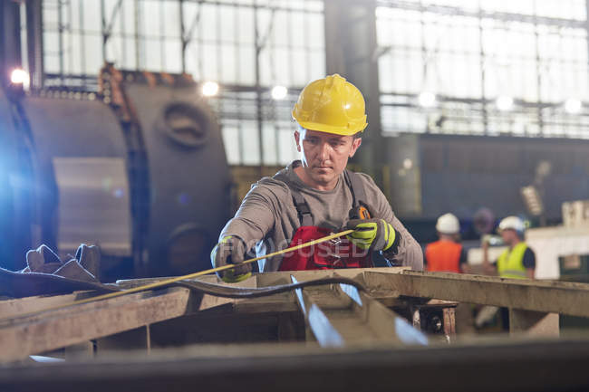 Чоловік працівник зі стрічкою вимірювальна сталь на заводі — стокове фото