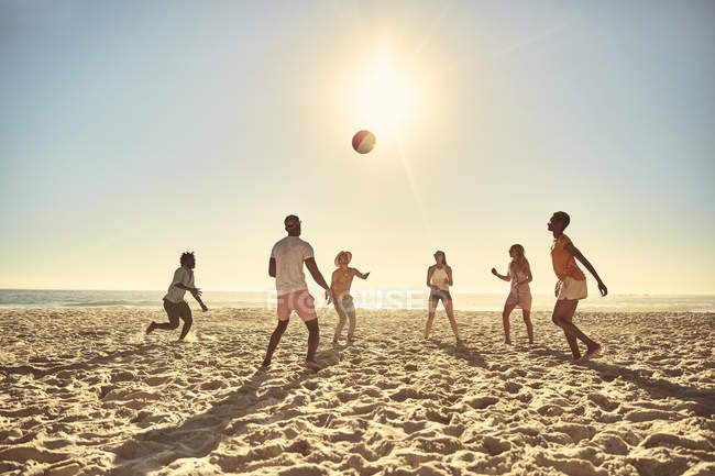 Jóvenes amigos jugando con pelota de playa en la soleada playa de verano - foto de stock