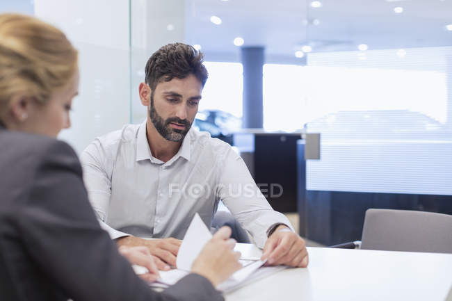 Car saleswoman explaining financial contract paperwork to male customer in car dealership office — Stock Photo
