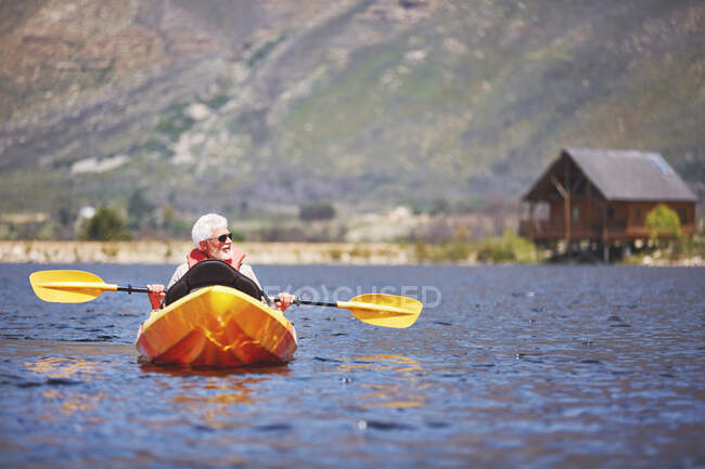 Uomo anziano kayak sul soleggiato lago estivo — Foto stock