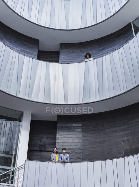 Portrait business people standing on architectural, modern office atrium balconies — Stock Photo