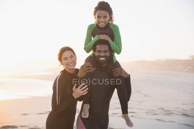 Портрет улыбается, счастливая семья в мокрых костюмах на солнечном летнем пляже — стоковое фото