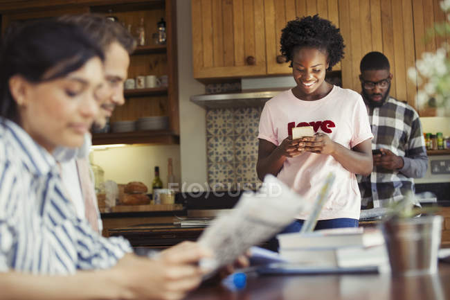 Женщина смс со смартфоном на кухне — стоковое фото