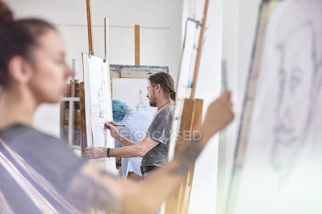 Artisti che disegnano ai cavalletti in studio di classe d'arte — Foto stock