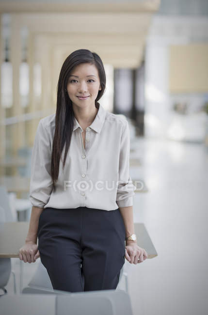 Retrato mujer de negocios confiada apoyada en el escritorio - foto de stock