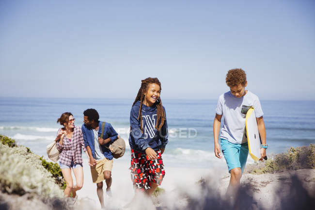 Семья, гуляющая с буги-бордом на солнечном пляже летнего океана — стоковое фото