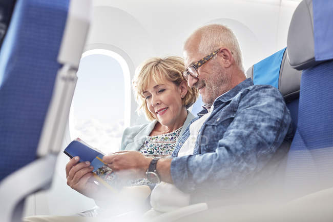 Älteres Paar liest Reiseführer im Flugzeug — Stockfoto