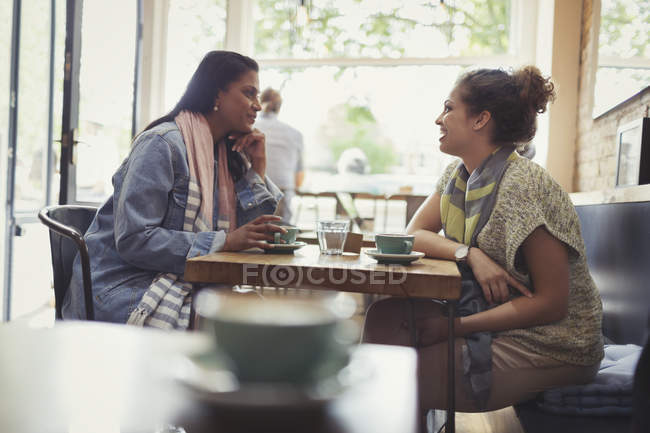 Women friends drinking coffee and talking at cafe table — Stock Photo