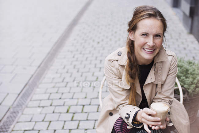Retrato sorrindo mulher bebendo café gelado no café da calçada — Fotografia de Stock