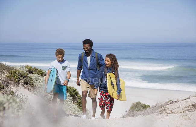 Семейная прогулка с буги-досками на солнечном летнем пляже океана — стоковое фото