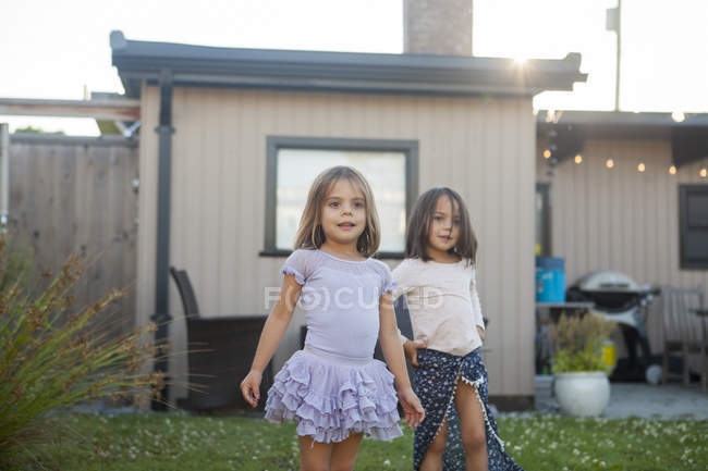 Portrait girl sisters in skirts in yard — Stock Photo