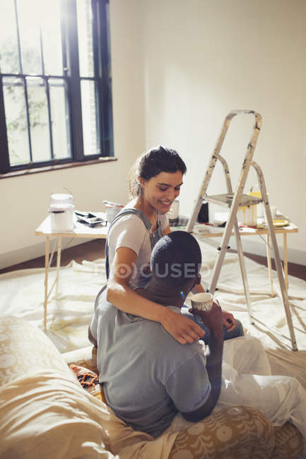 Carinhoso jovem casal abraço, pintura sala de estar — Fotografia de Stock