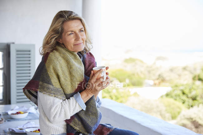 Serene woman drinking coffee on patio — Stock Photo
