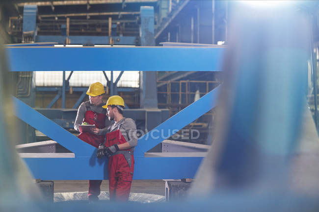 Male workers with clipboard talking in factory — Stock Photo