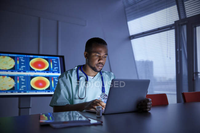 Medico maschio concentrato che lavora al computer portatile in ospedale — Foto stock