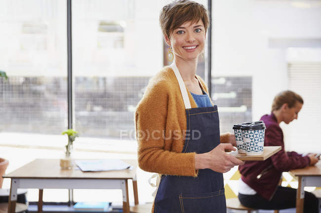Retrato confiado propietario de café femenino que sirve café en bandeja en la cafetería - foto de stock