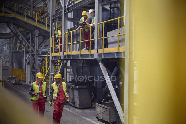 Steelworkers talking and walking in steel mill — Stock Photo