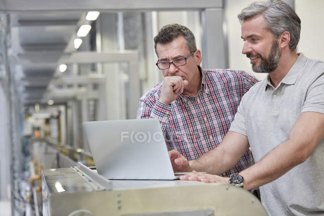 Male supervisors using laptop in factory — Stock Photo
