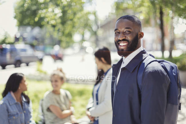 Retrato sorridente empresário com mochila no parque urbano — Fotografia de Stock