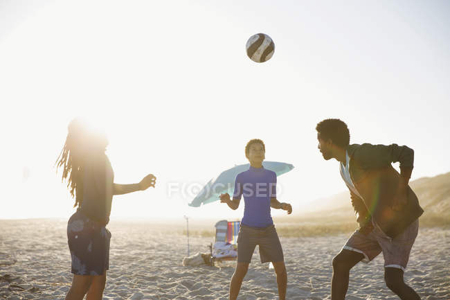 Семья играет в футбол на солнечном пляже летом — стоковое фото