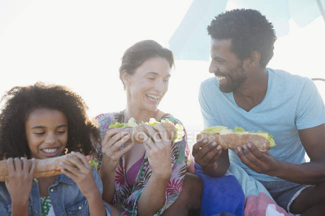 Familia multiétnica comiendo sándwiches de baguette - foto de stock