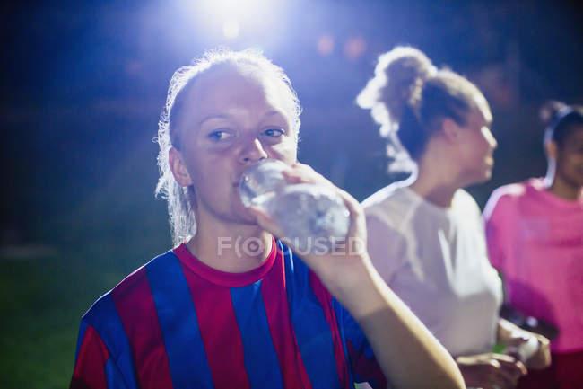 Jovem jogadora de futebol bebendo de garrafa de água — Fotografia de Stock