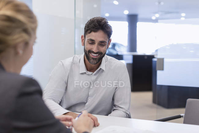 Sorrindo cliente masculino ouvir vendedor de carros no escritório concessionária de automóveis — Fotografia de Stock