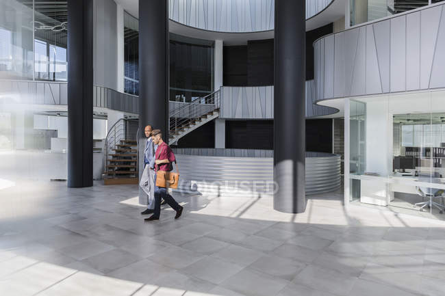 Empresarios caminando en moderno vestíbulo de oficinas - foto de stock