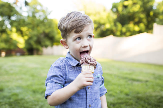 Preschool boy eating ice cream cone in summer yard — Stock Photo