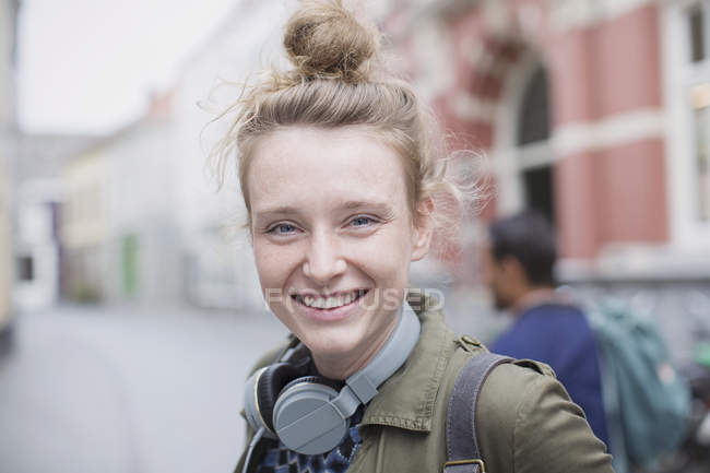 Портрет улыбающейся молодой женщины в наушниках на городской улице — стоковое фото