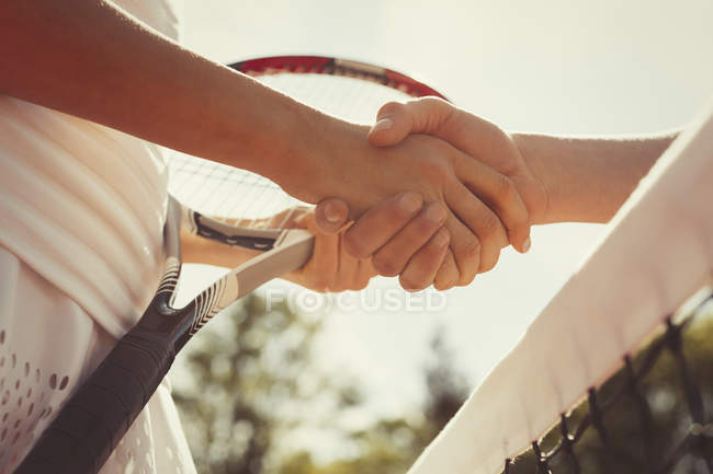 Close up tennis players handshaking in sportsmanship at net — Stock Photo