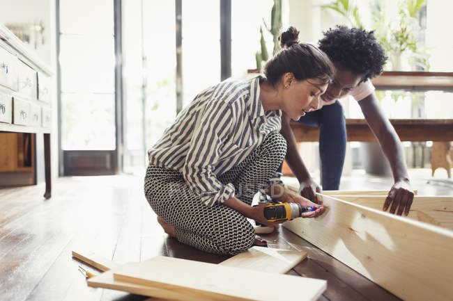 Young women assembling furniture with power drill — Stock Photo