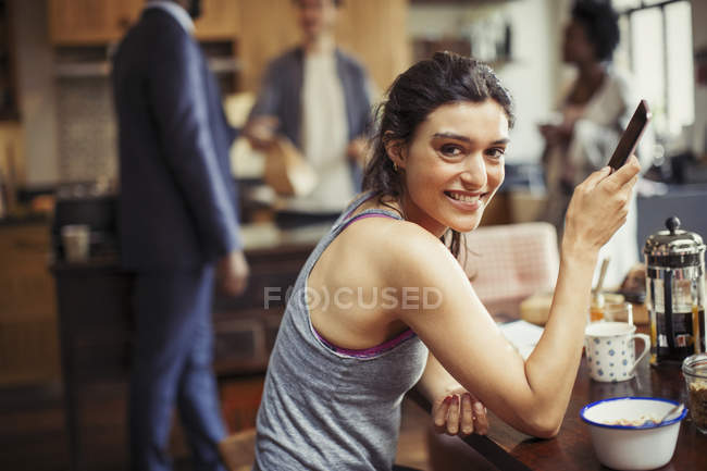 Ritratto sorridente giovane donna sms con smart phone a tavola colazione — Foto stock