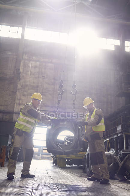 Métallurgistes déplaçant une pièce en acier dans une aciérie — Photo de stock