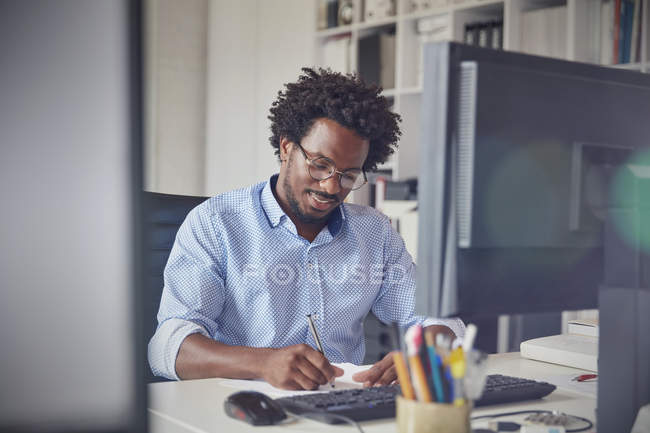 Бізнесмен робить нотатки за комп'ютером в офісі — стокове фото