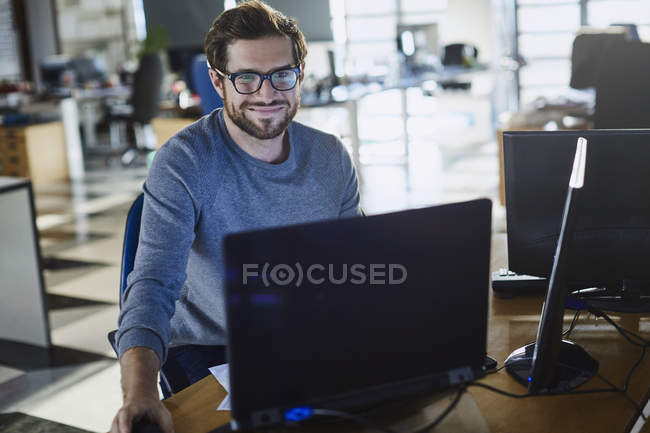 Porträt lächelnder Geschäftsmann, der im Büro am Computer arbeitet — Stockfoto