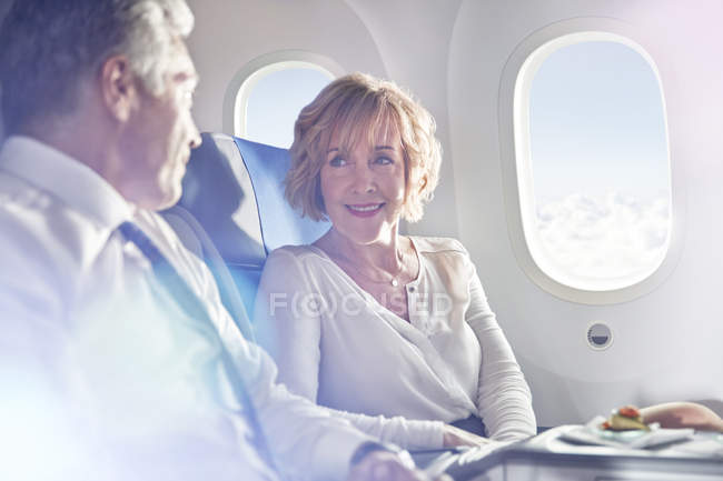 Empresario y empresaria hablando en primera clase en avión - foto de stock