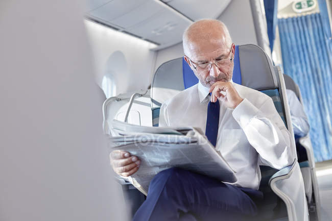 Empresário lendo jornal no avião — Fotografia de Stock