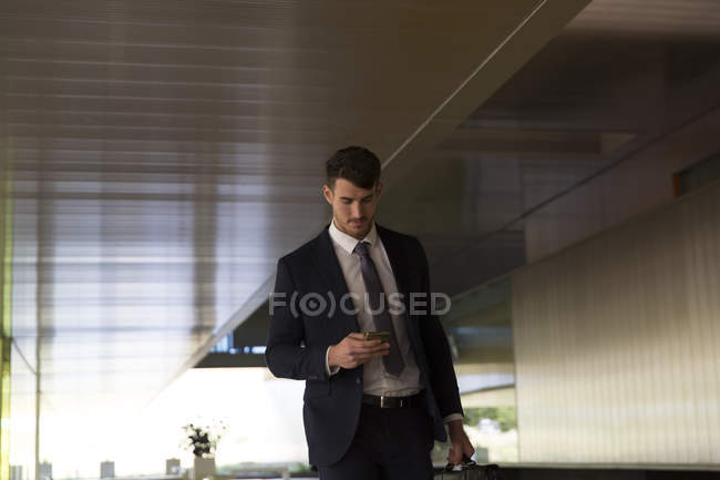 Businessman texting with smart phone in office lobby — Stock Photo