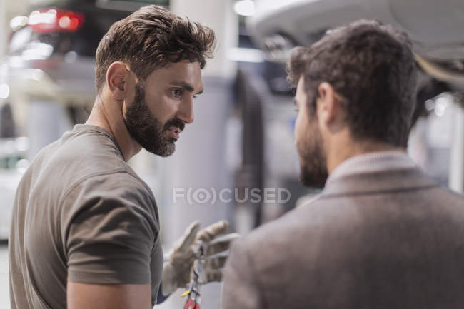 Auto mecânica falando, explicando ao cliente na oficina de reparação de automóveis — Fotografia de Stock