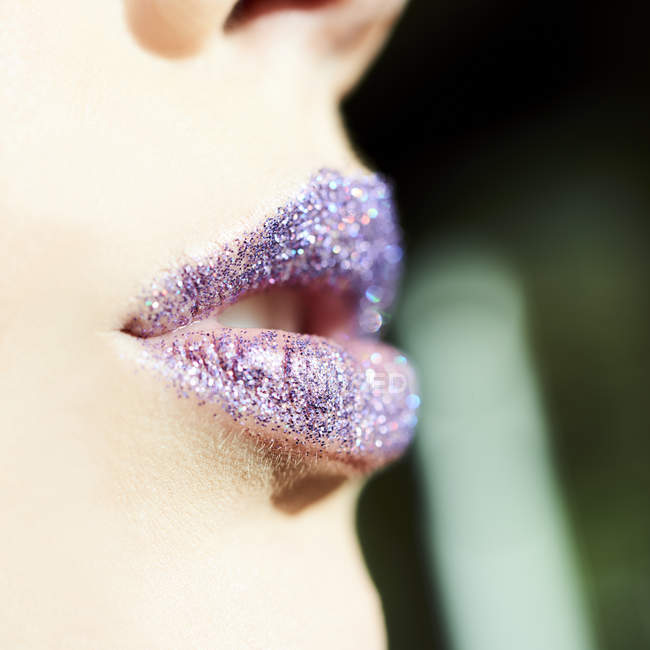 Nahaufnahme lila Glitzern auf den Lippen der Frau, verschwommener Hintergrund — Stockfoto