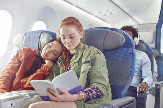 Liebevolles junges lesbisches Paar schläft und liest im Flugzeug — Stockfoto