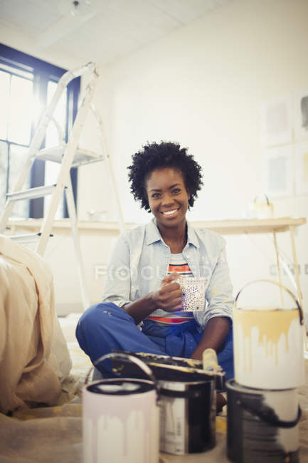 Retrato sorrindo mulher bebendo café, pintura sala de estar — Fotografia de Stock