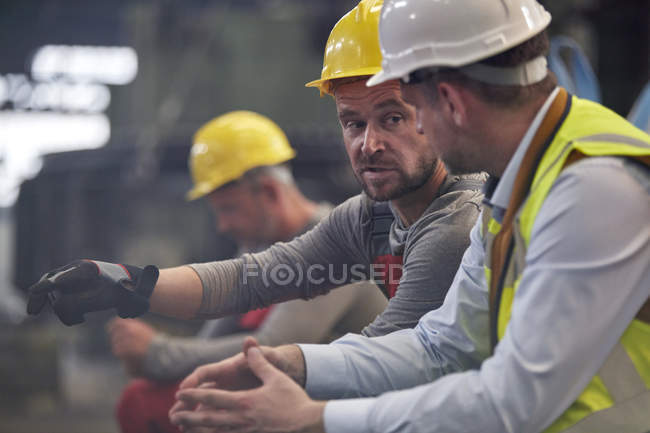 Рабочие-мужчины разговаривают на заводе — стоковое фото