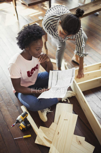 Women assembling furniture, reading instructions — Stock Photo