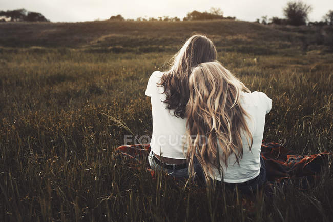 Tranquil adolescente hermanas en camisetas blancas en el campo rural - foto de stock