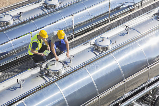 Workers on platform above stainless steel milk tanker — Stock Photo