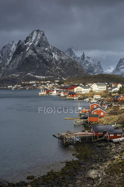 Fishing village at waterfront below rugged mountains, Reine, Lofoten, Norway — Stock Photo
