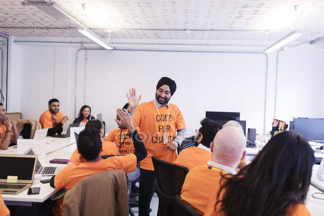Hackers comemorando, high-fiving e codificação para caridade no hackathon — Fotografia de Stock