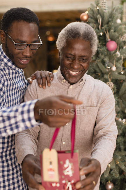 Petit-fils surprenant grand-père avec cadeau de Noël — Photo de stock